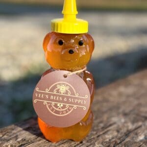 A bear shaped honey bottle sitting on top of a wooden table.