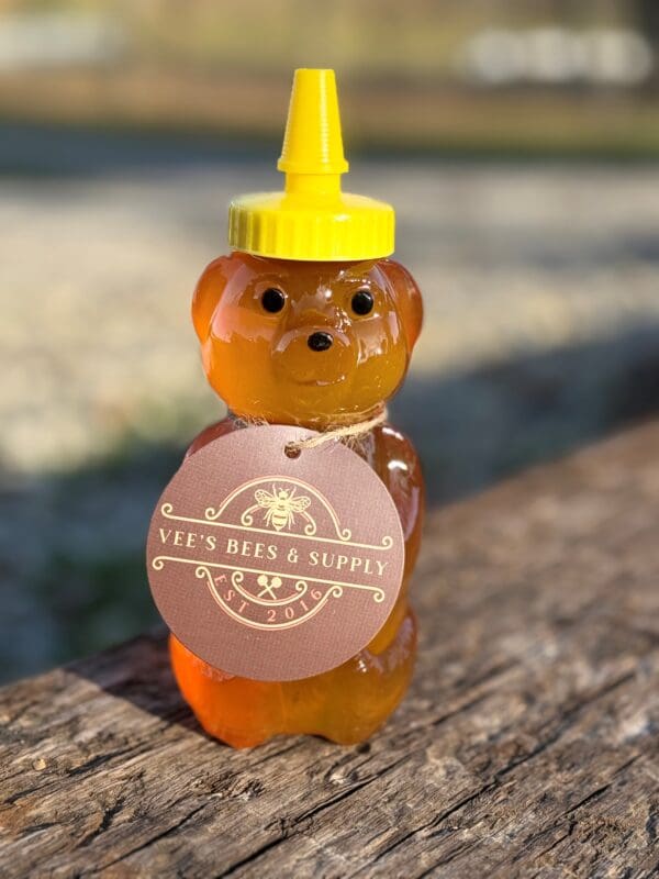 A bear shaped honey bottle sitting on top of a wooden table.