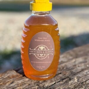 A bottle of honey sitting on top of a wooden table.