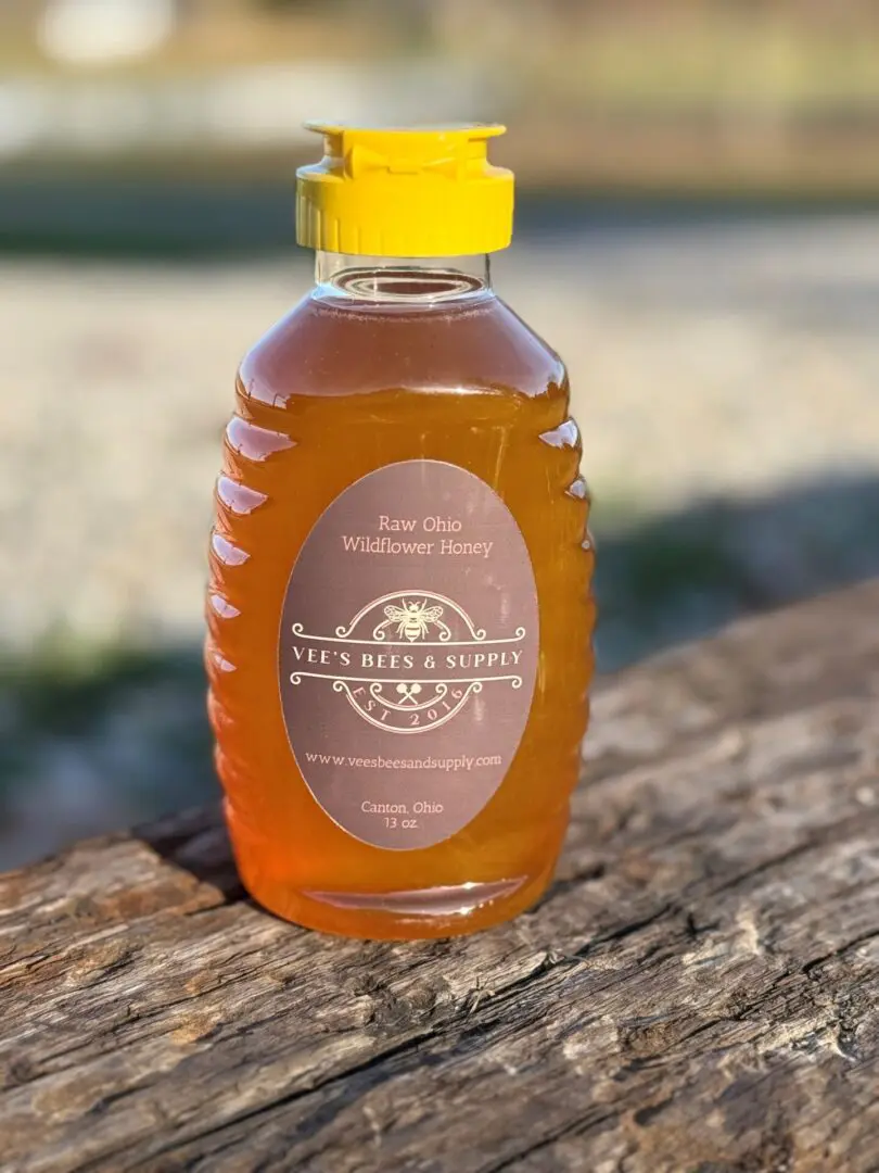 A bottle of honey sitting on top of a wooden table.