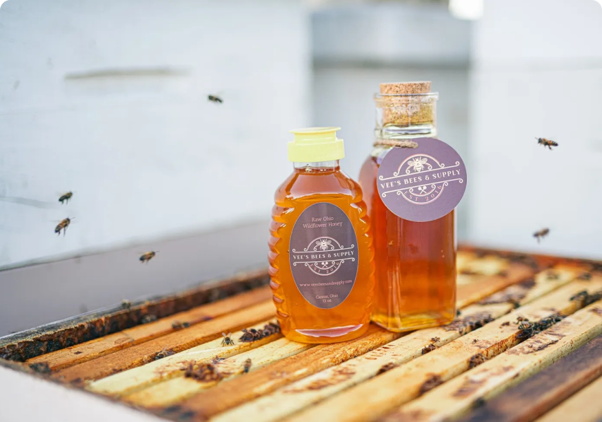 A close up of two bottles of honey on top of some wood